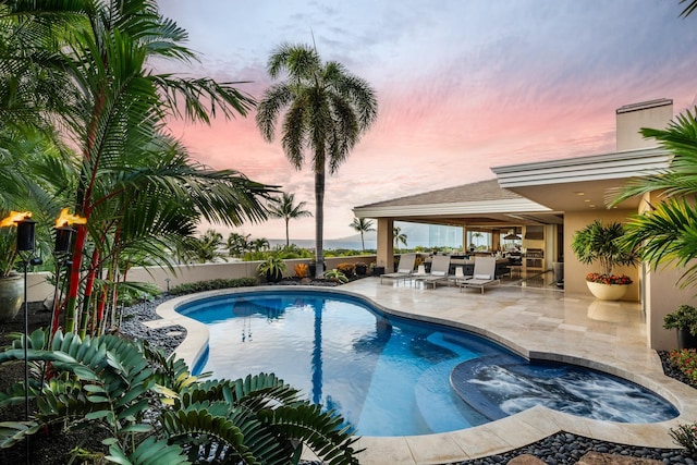 pool at dusk featuring an in ground hot tub, a patio, and a fenced in pool