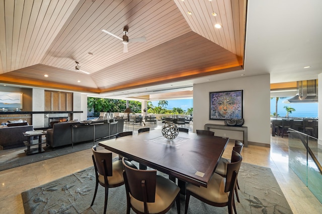 dining room with a large fireplace, a tray ceiling, wood ceiling, and recessed lighting