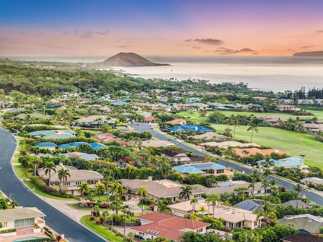 aerial view at dusk featuring a water view and a residential view