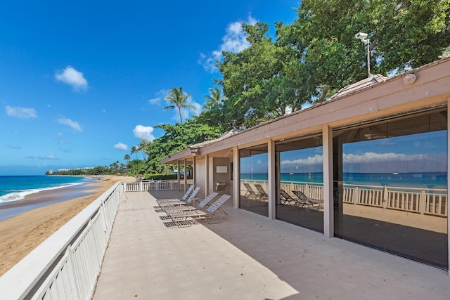 view of patio / terrace featuring a water view and a beach view