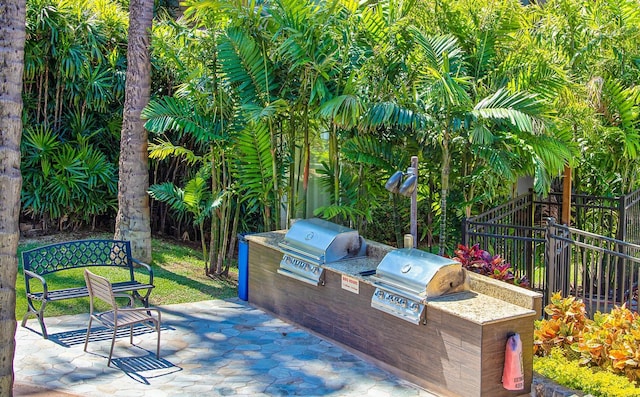 view of patio featuring a grill, fence, and an outdoor kitchen