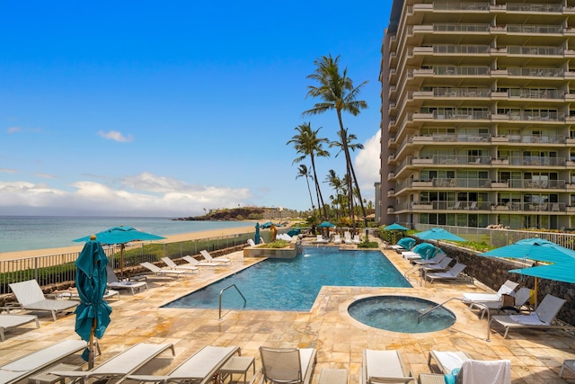 view of swimming pool with a water view, a patio area, and a hot tub