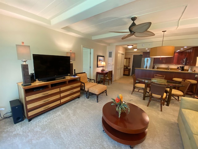 carpeted living room with beam ceiling and ceiling fan