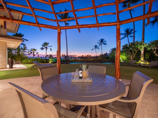 patio terrace at dusk featuring a yard