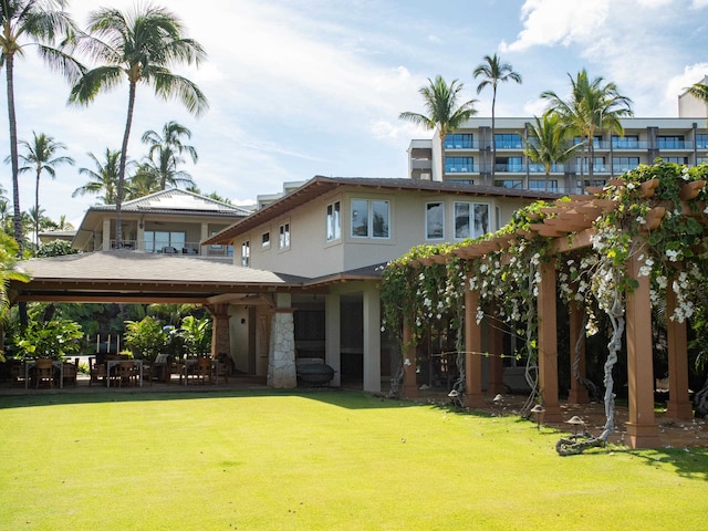 rear view of house featuring a pergola and a lawn