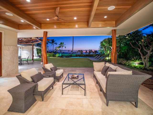 patio terrace at dusk featuring ceiling fan, a lawn, and an outdoor hangout area