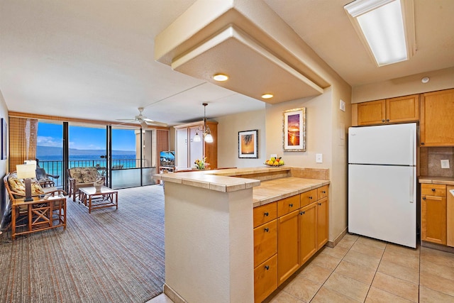 4327 Lower Honoapiilani Rd Unit 1002B, Lahaina, HI 96761 - kitchen featuring freestanding refrigerator, tile counters, a peninsula, a water view, and ceiling fan