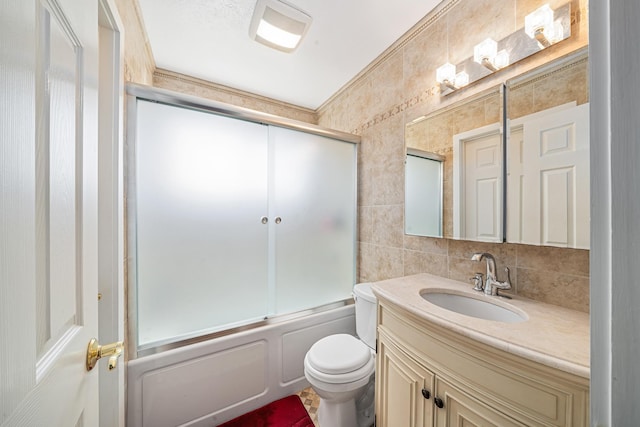 full bath featuring toilet, shower / bath combination with glass door, tile walls, decorative backsplash, and vanity