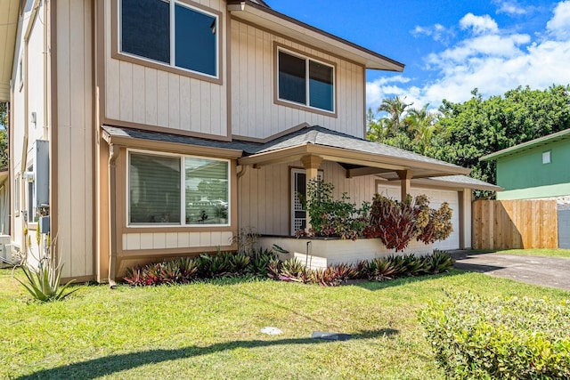 view of front of home with driveway, a front lawn, and fence