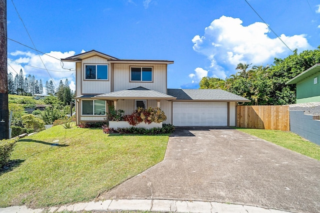 traditional-style home with driveway, a front lawn, fence, a shingled roof, and a garage