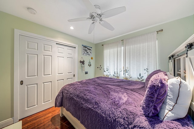 bedroom with a closet, a barn door, a ceiling fan, and wood finished floors