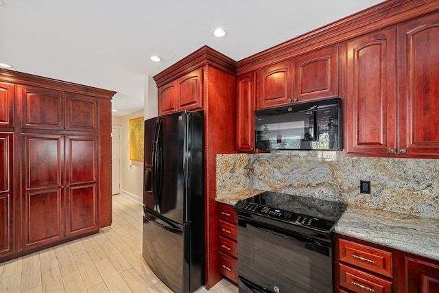 kitchen with light stone counters, dark brown cabinets, and black appliances