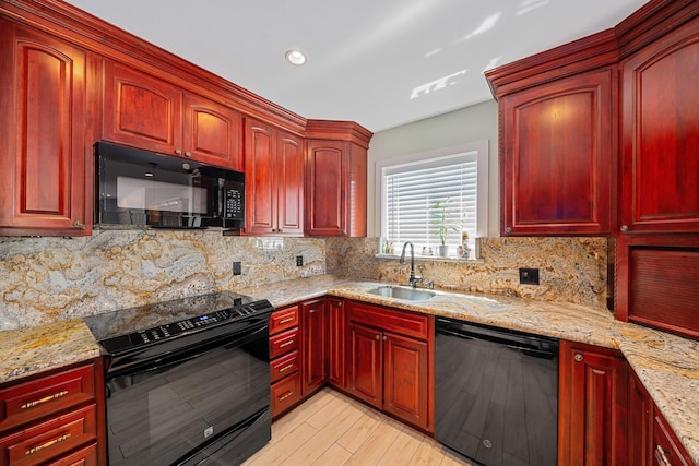 kitchen featuring black appliances, light stone counters, a sink, backsplash, and dark brown cabinets