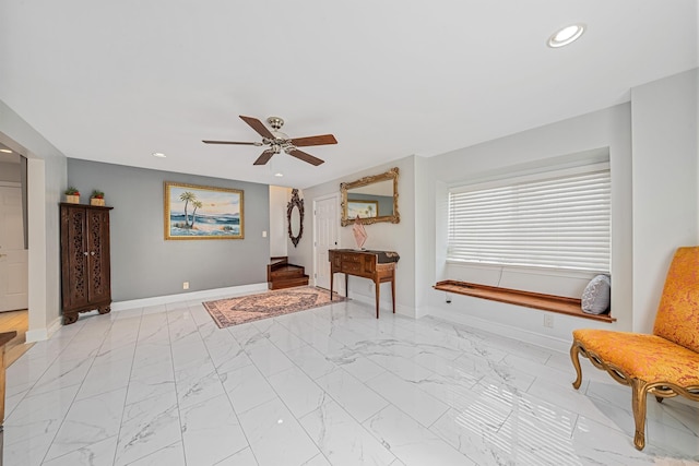 living area with a ceiling fan, recessed lighting, marble finish floor, and baseboards