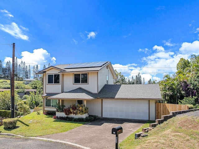 view of front of property with fence, a front yard, roof mounted solar panels, a garage, and driveway