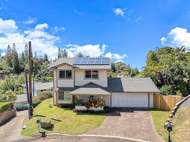 traditional-style home featuring driveway, fence, roof with shingles, a front yard, and a garage