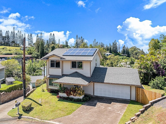 view of front of property featuring solar panels, fence, a front yard, driveway, and an attached garage