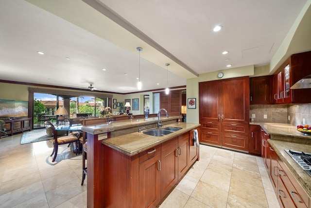 kitchen with decorative backsplash, a kitchen breakfast bar, ceiling fan, sink, and a center island with sink