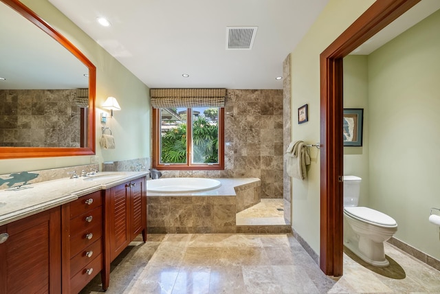 bathroom with vanity, toilet, and tiled tub