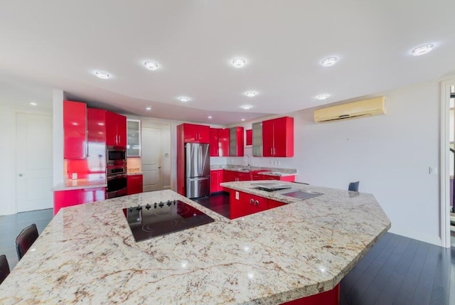 kitchen with a spacious island, sink, light stone counters, stainless steel appliances, and a wall unit AC