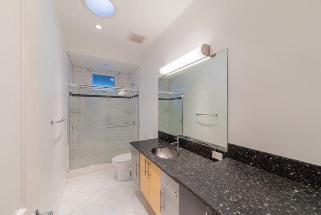 bathroom featuring tile patterned floors, vanity, toilet, and a shower with door