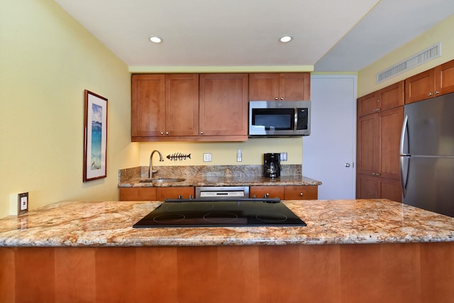 kitchen featuring kitchen peninsula, light stone counters, sink, and appliances with stainless steel finishes