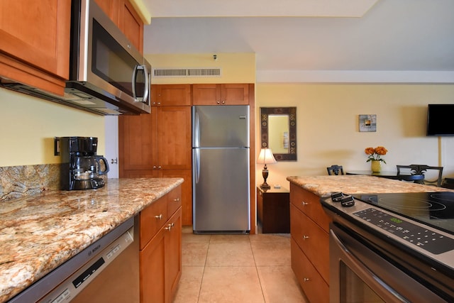 kitchen with light stone counters, light tile patterned floors, and appliances with stainless steel finishes