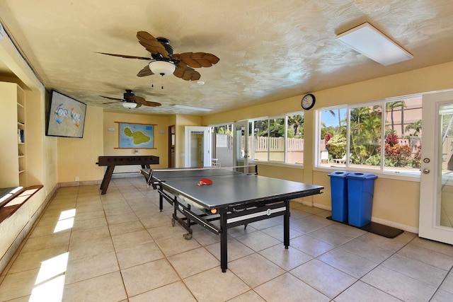 rec room featuring a skylight, ceiling fan, and light tile patterned flooring