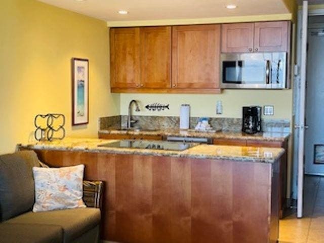 kitchen featuring kitchen peninsula, light tile patterned floors, black electric cooktop, and light stone countertops