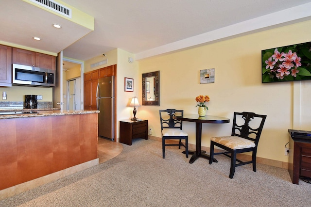 kitchen featuring dark stone countertops, light colored carpet, and appliances with stainless steel finishes