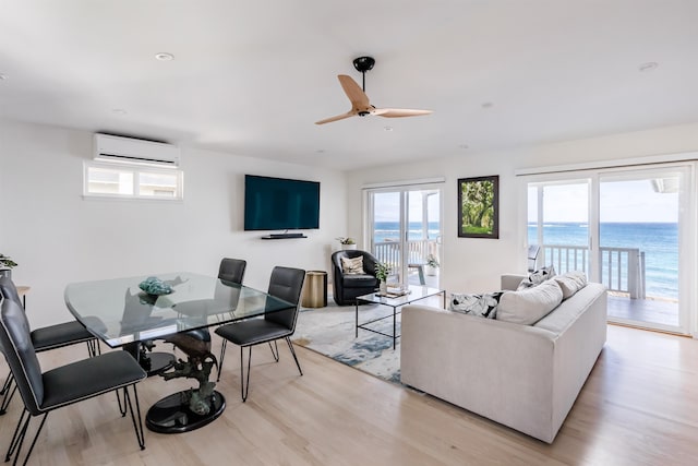 living room with ceiling fan, a healthy amount of sunlight, light hardwood / wood-style floors, and a wall unit AC