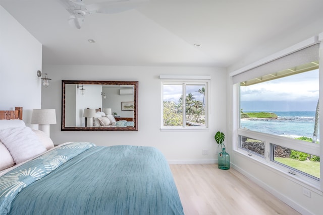 bedroom with ceiling fan, a water view, light wood-type flooring, and vaulted ceiling