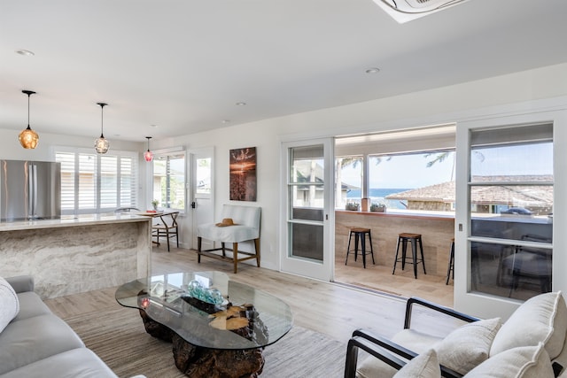 living room with plenty of natural light, a water view, and light wood-type flooring