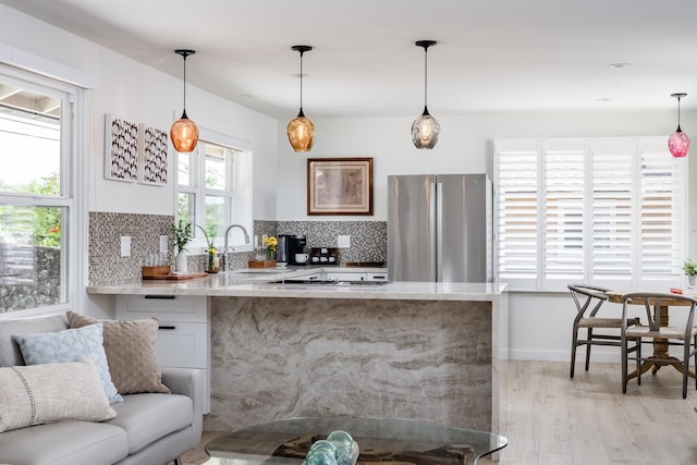 kitchen with decorative light fixtures, light hardwood / wood-style floors, white cabinetry, and stainless steel refrigerator