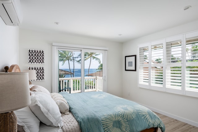 bedroom with a wall unit AC, a water view, access to outside, and multiple windows