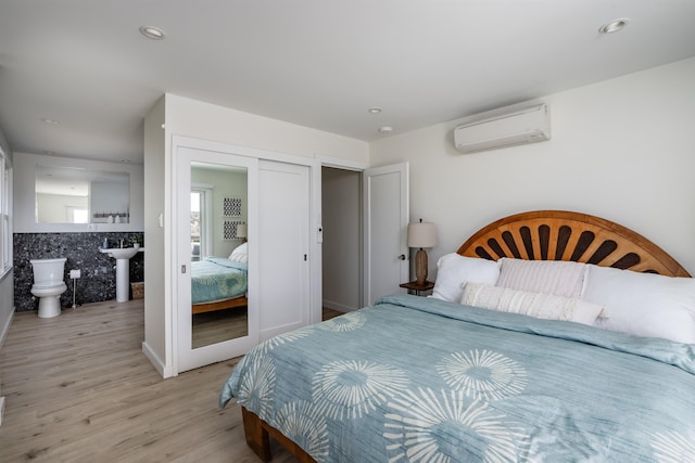 bedroom with a wall unit AC and light hardwood / wood-style flooring