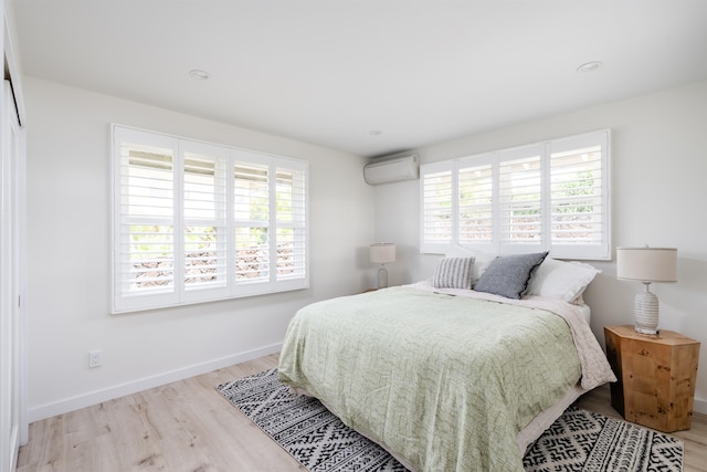 bedroom featuring light wood-type flooring and a wall mounted AC