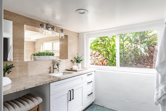 bathroom with vanity, backsplash, and tile walls