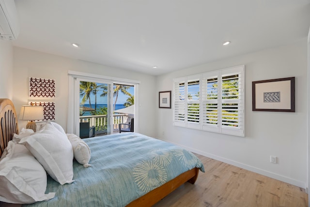 bedroom featuring access to outside, an AC wall unit, and light hardwood / wood-style floors