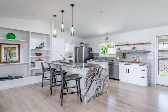 kitchen featuring appliances with stainless steel finishes, sink, white cabinets, light hardwood / wood-style floors, and lofted ceiling