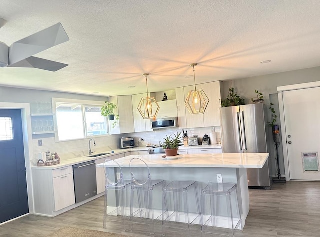 550 Kailana St, Wailuku, HI 96793 - kitchen with stainless steel appliances, a sink, a kitchen island, a breakfast bar, and backsplash