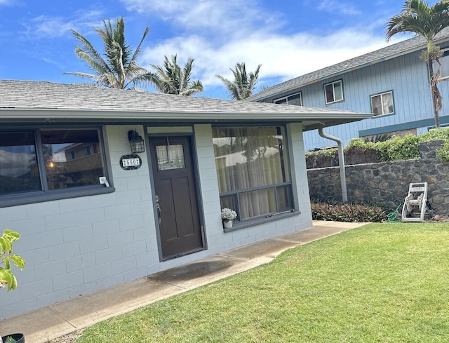 550 Kailana St, Wailuku, HI 96793 - view of exterior entry featuring a lawn, a shingled roof, and concrete block siding
