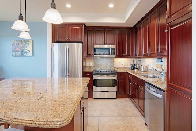 kitchen featuring light stone countertops, a sink, stainless steel appliances, backsplash, and pendant lighting