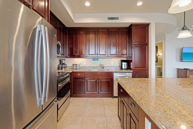 kitchen with visible vents, tasteful backsplash, a sink, reddish brown cabinets, and stainless steel appliances