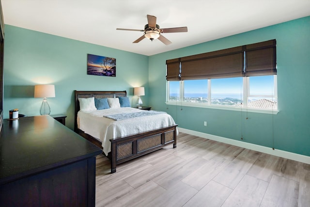 bedroom featuring a ceiling fan, baseboards, and light wood-type flooring