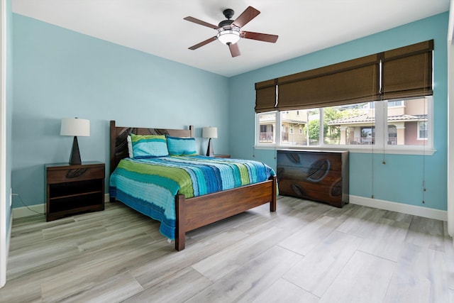 bedroom with baseboards, ceiling fan, and light wood-style flooring