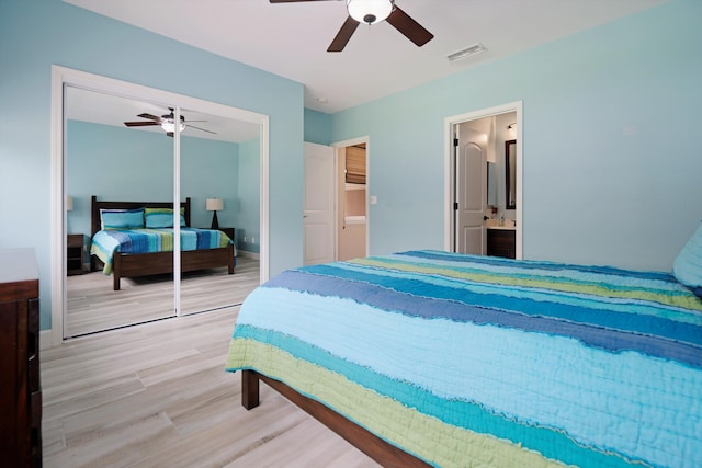 bedroom featuring ceiling fan, ensuite bath, wood finished floors, visible vents, and a closet