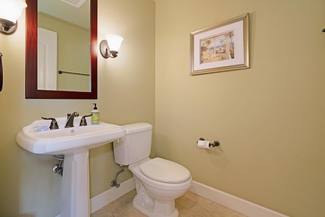 bathroom featuring baseboards, tile patterned flooring, and toilet