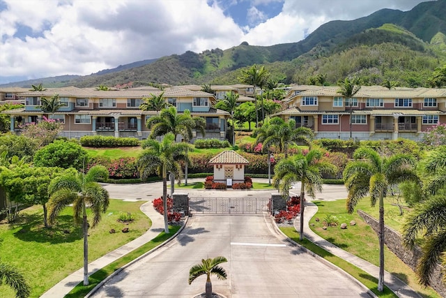 exterior space featuring a gated entry, a residential view, a mountain view, and curbs
