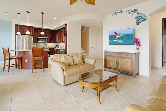 living room with visible vents, stairway, recessed lighting, arched walkways, and light tile patterned floors